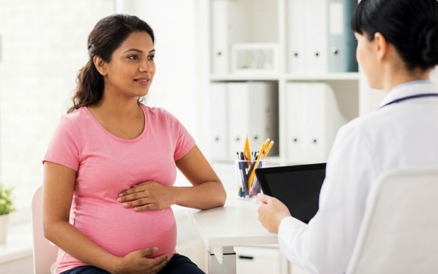 Pregnant woman consulting with a doctor in a medical office, focusing on maternal care.